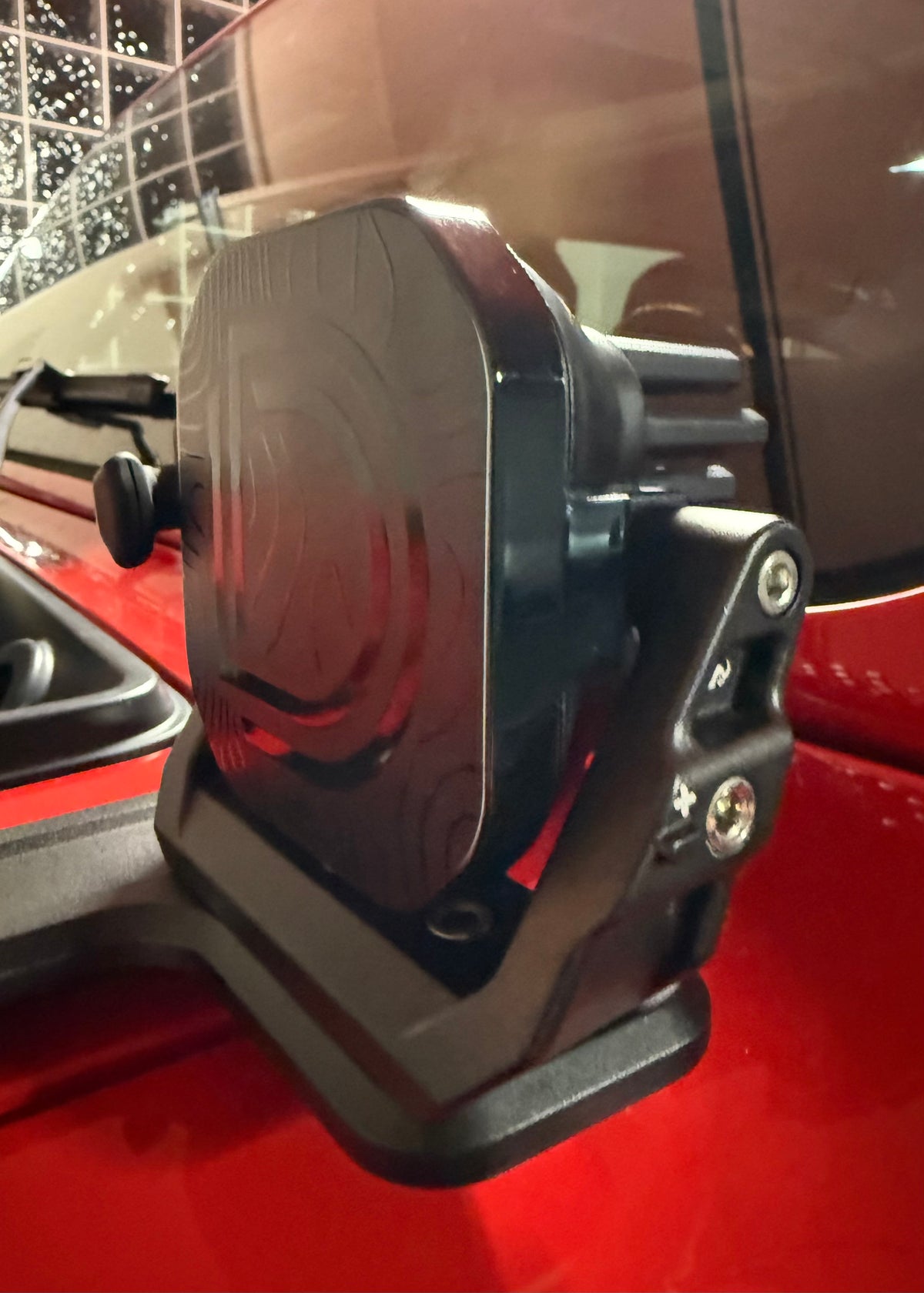 Black off road light in mounts, on a red vehicle.  