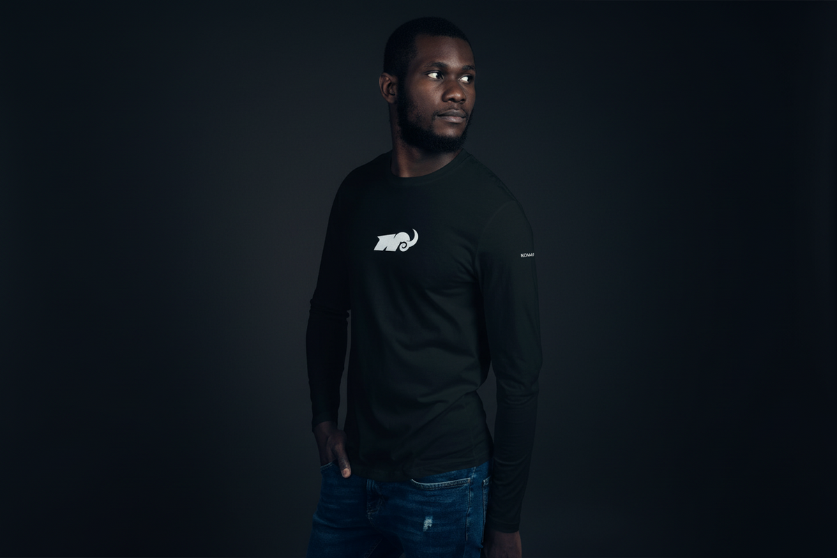 Man wearing a black long-sleeve shirt with a logo on a dark background
